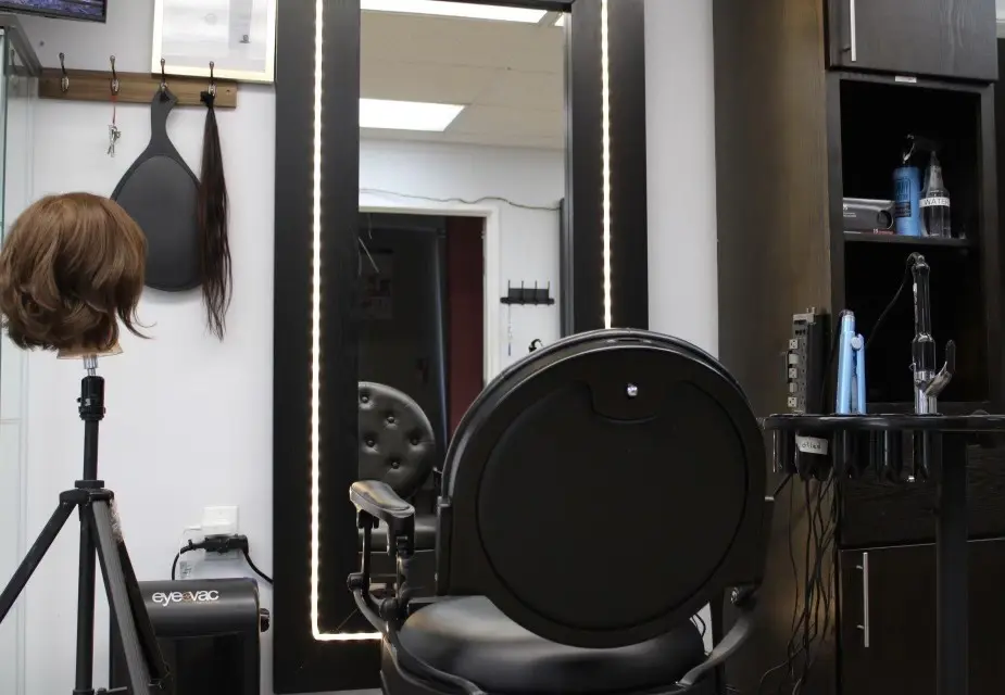 A chair in front of a mirror and hair dryer.