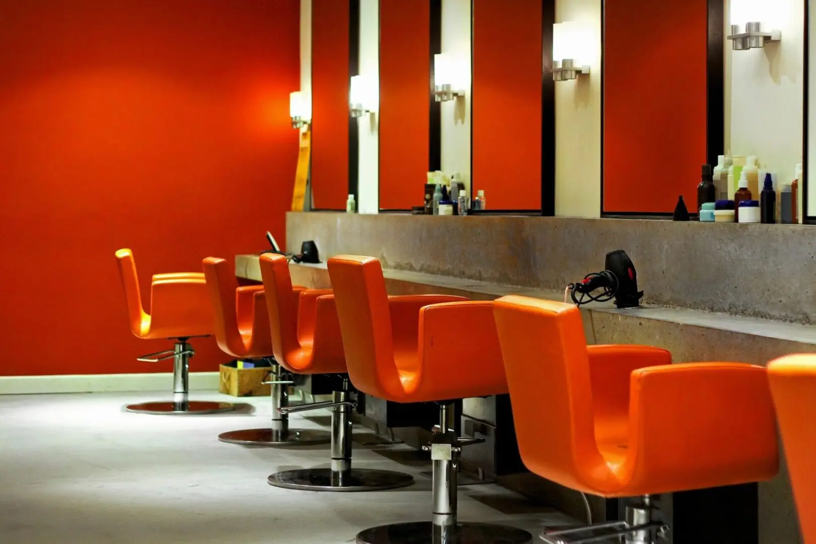 A row of orange chairs in front of mirrors.